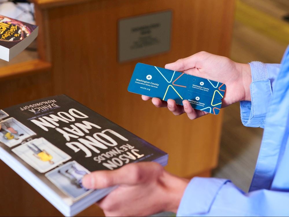 A library patron holding their library card